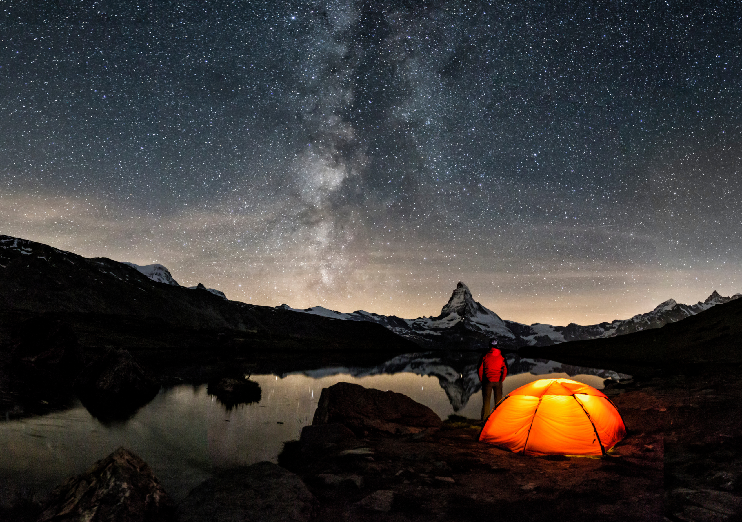 Céu noturno sobre montanhas com trailer e barraca
